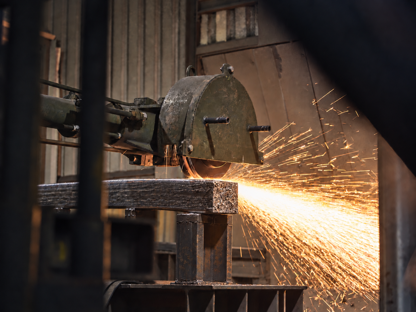 Square-section billet being machine-ground with flying sparks